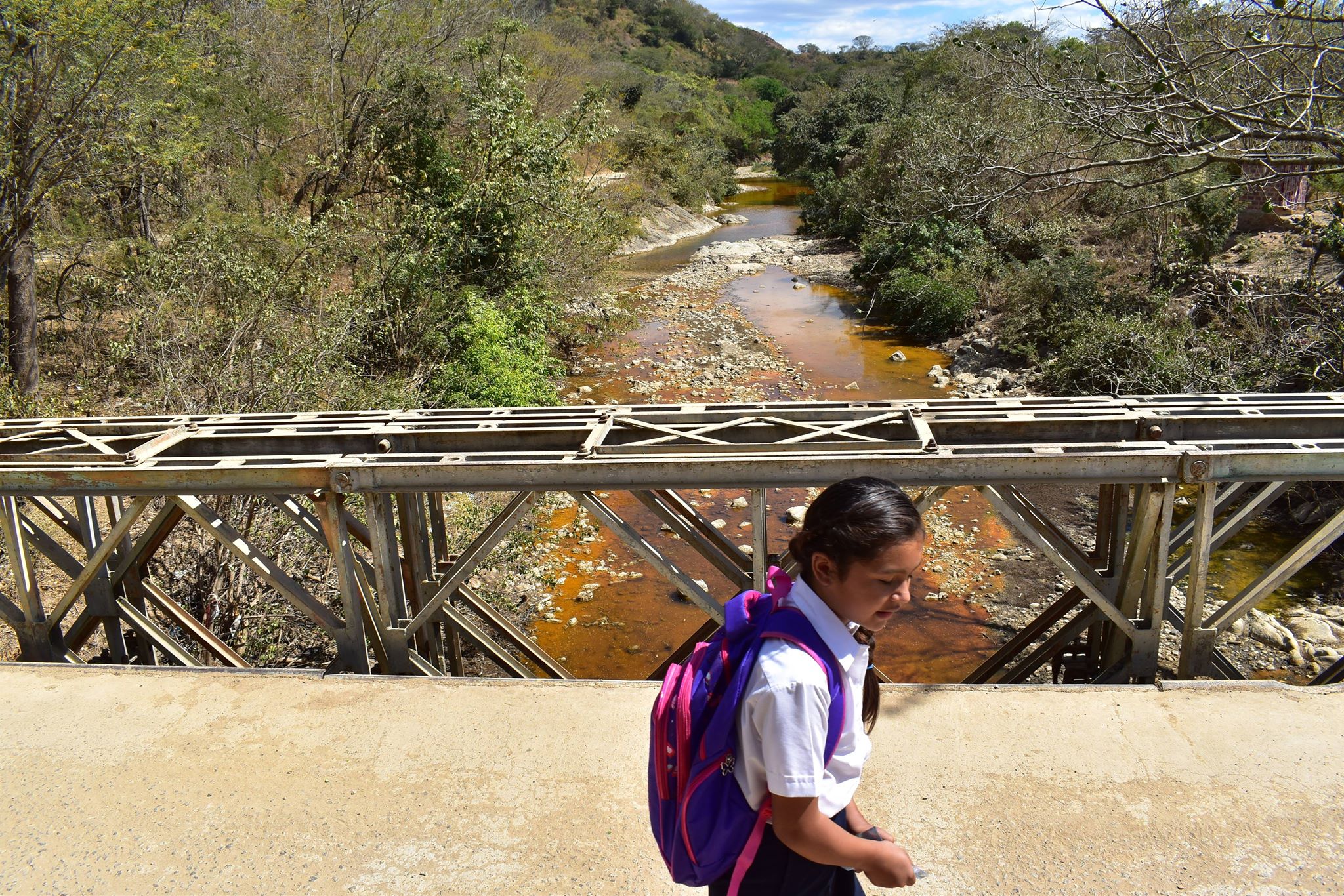 Niña regresa de escuela atravesando puente